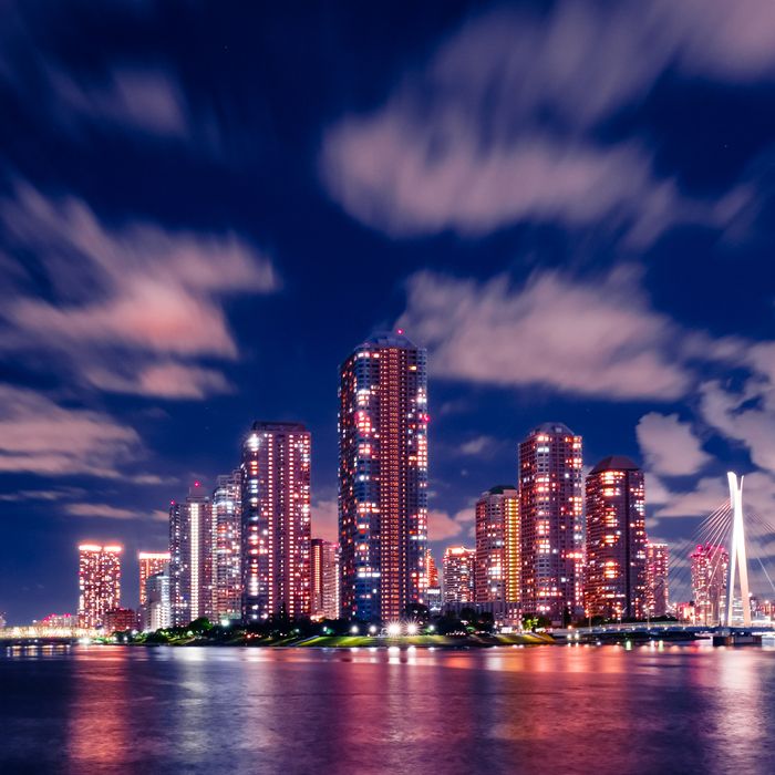 Beautiful night view of Tokyo skyline with illuminated skyscrapers reflecting on water.
