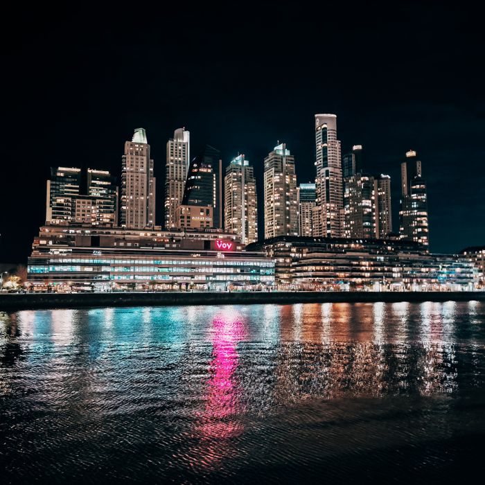 Night view of a city skyline with vibrant lights reflecting on the river water.