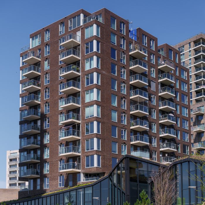 Modern apartment building with distinct balconies in Almere, Netherlands, under clear blue sky.