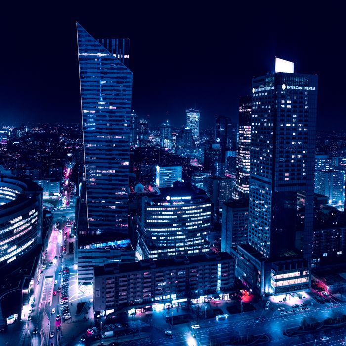 Experience the dazzling night skyline of Warsaw with illuminated skyscrapers and vibrant city lights.